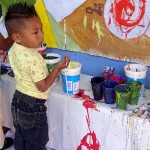 Ein Kind malt an dem Wandbild bei der Veranstaltung zum 20. Geburtstag von SIPAZ mit © SIPAZ